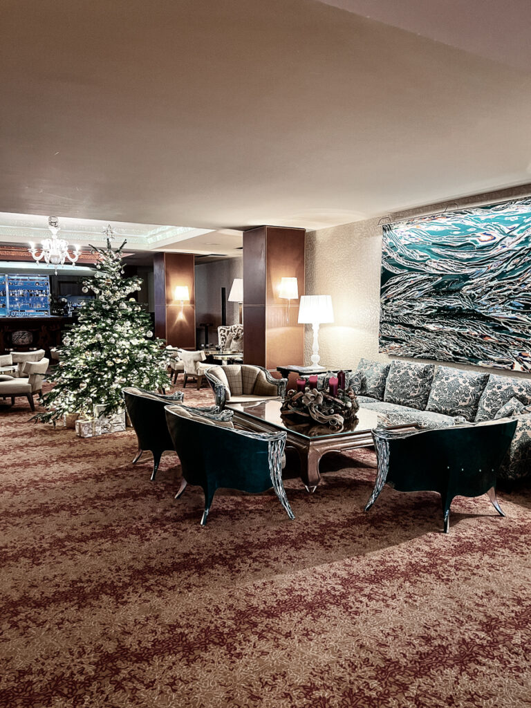 Tschuggen Grand Hotel lobby has a modern sitting area with sofas and a decorated Christmas tree in the middle.