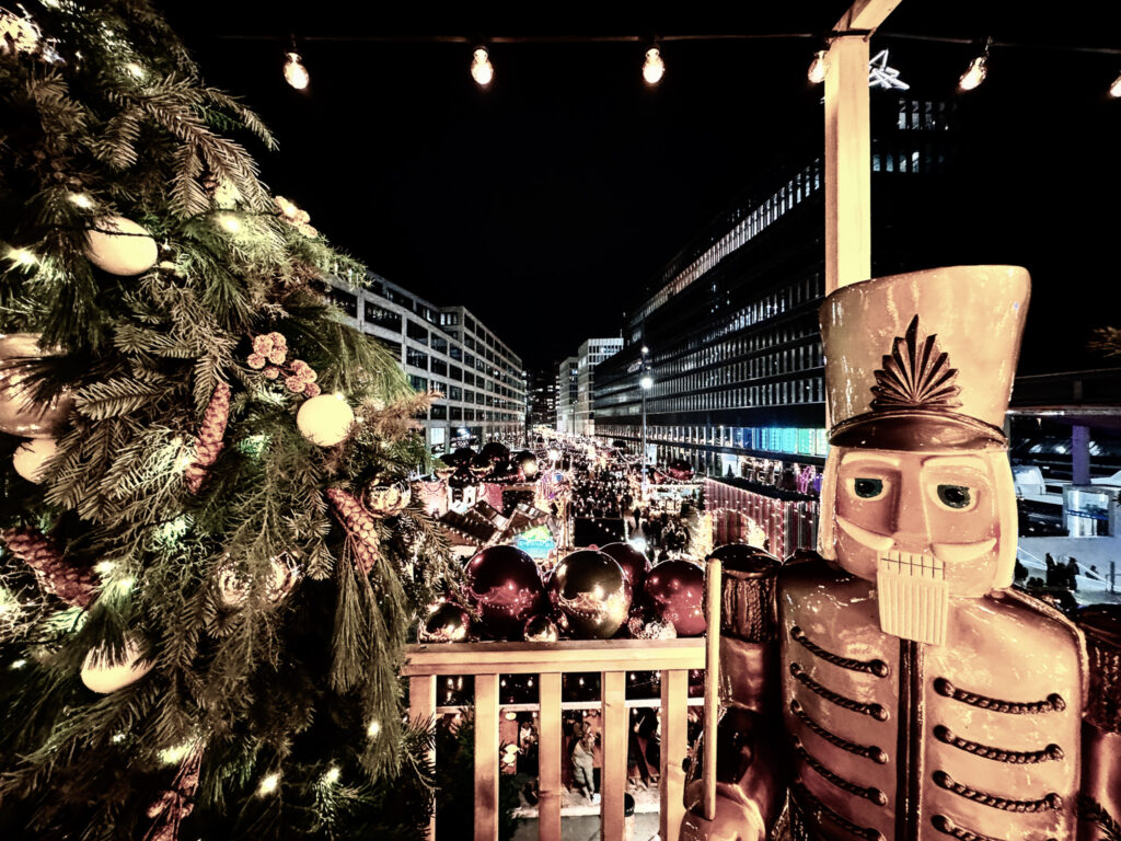 Decorated Christmas tree and large nutcracker figure overlooking the illuminated Weihnachtsallee Market in Zurich.