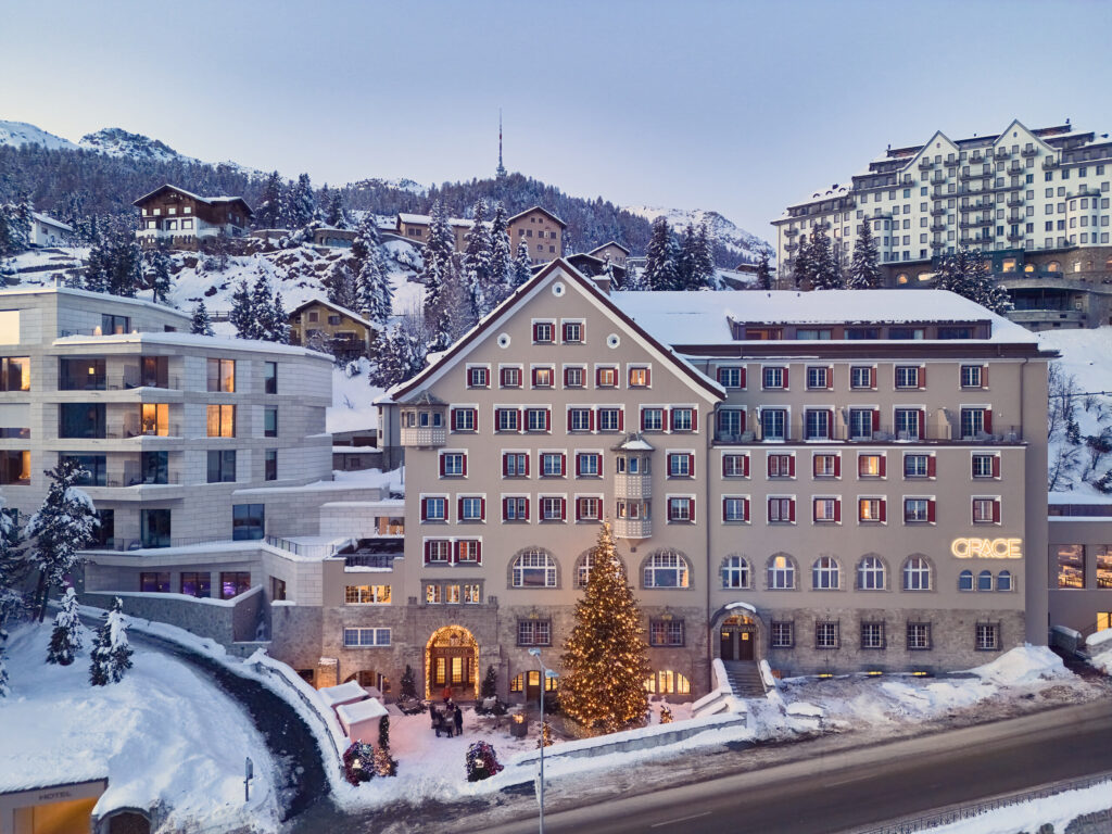 Aerial view of GRACE LA MARGNA ST MORITZ in winter, with snow on the roofs, a lit Christmas tree in front and the village behind